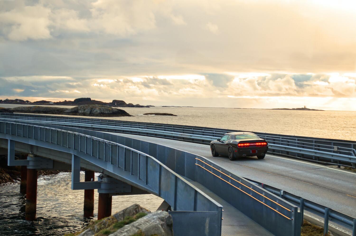 Car going across bridge with ocean backdrop